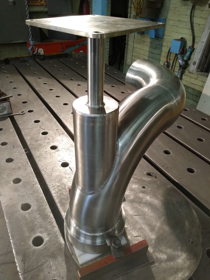 Polished stainless process piping fitting on fabrication table